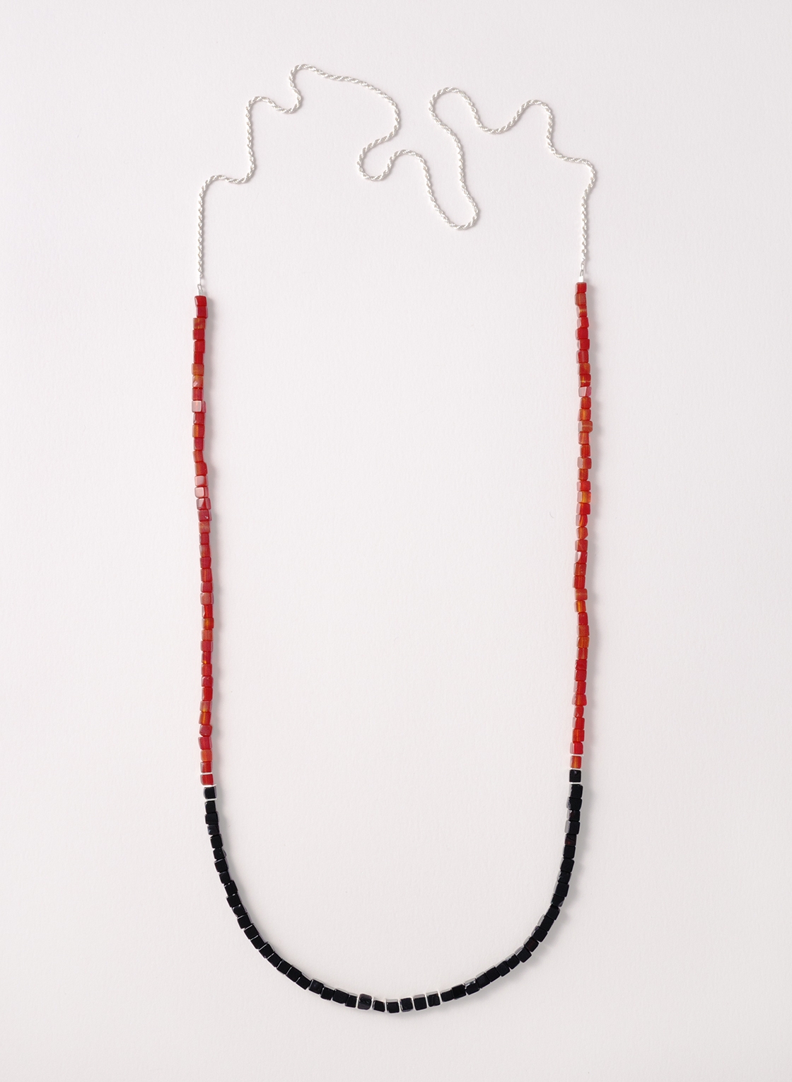 Silberne Kordelkette mit rotem Karneol und schwarzem Onyx in Würfelform. Kombiniert mit silbernen Zwischenelementen und einer Kordelkette aus Sterling Silber.