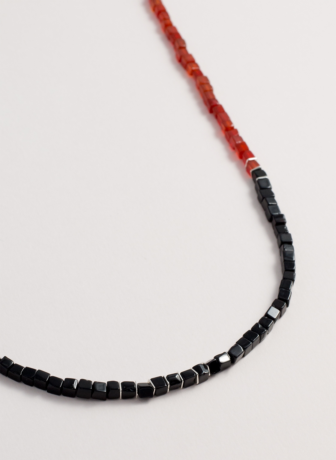 Silberne Kordelkette mit rotem Karneol und schwarzem Onyx in Würfelform. Kombiniert mit silbernen Zwischenelementen und einer Kordelkette aus Sterling Silber.